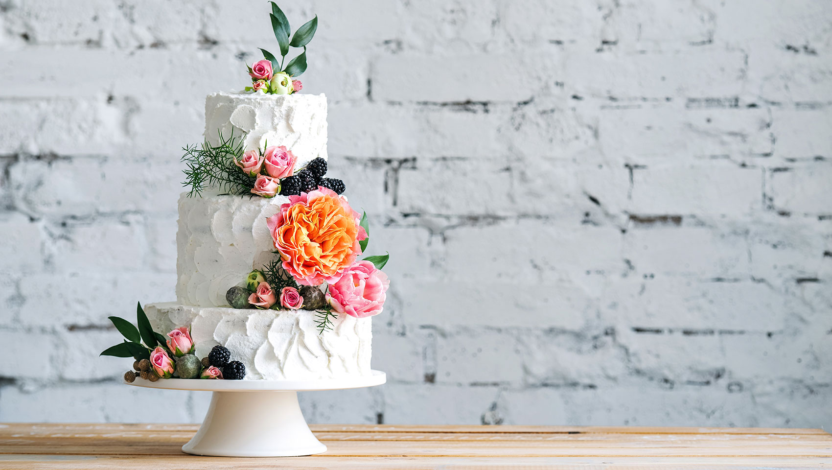 Tier wedding cake with white brick wall in the background
